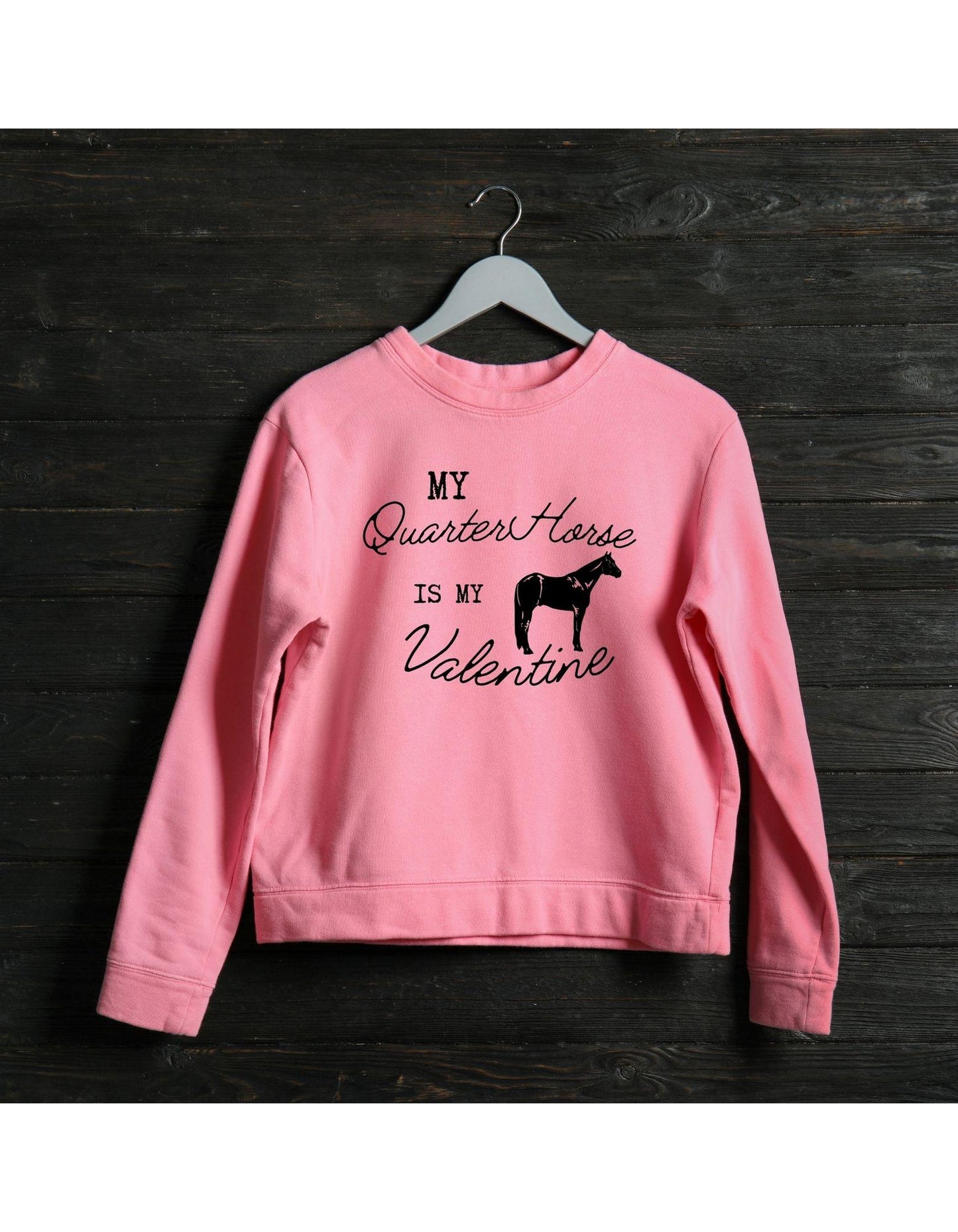 Pink sweatshirt with text and horse graphic on a wooden background