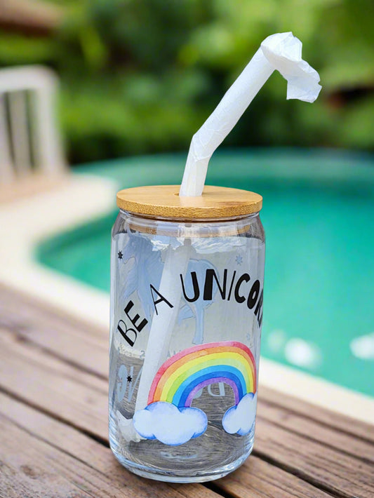 Clear tumbler with rainbow design and straw on a wooden surface