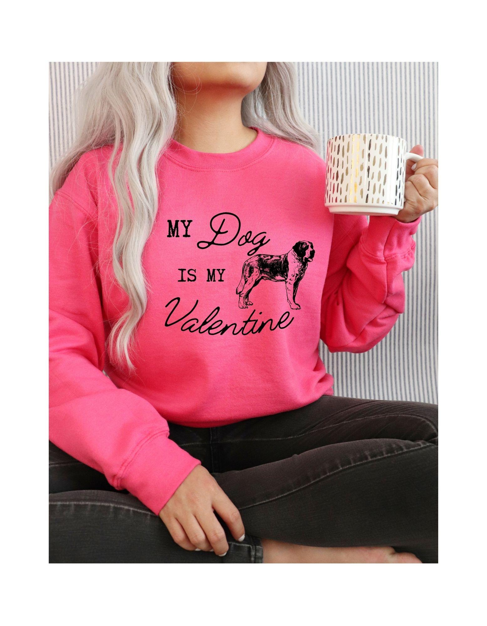 Person wearing a pink sweatshirt with 'My Dog is My Valentine' text and holding a mug.