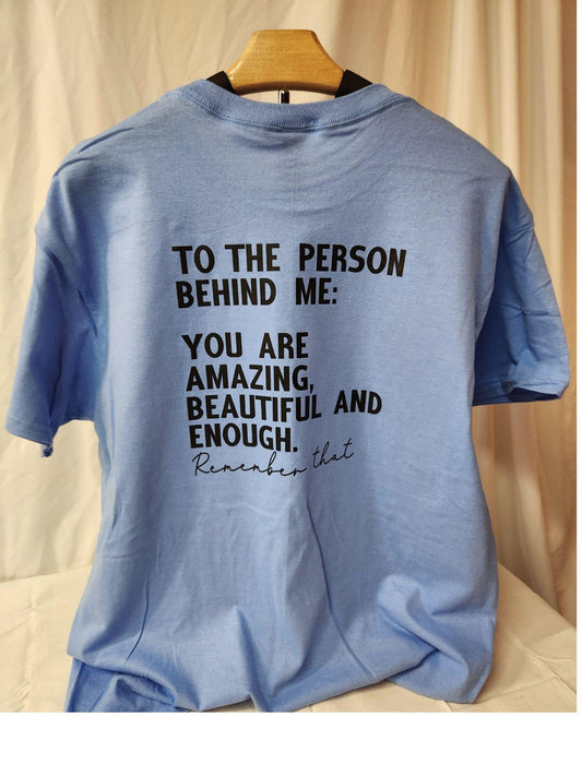 Blue t-shirt with motivational message on a wooden hanger against a beige background