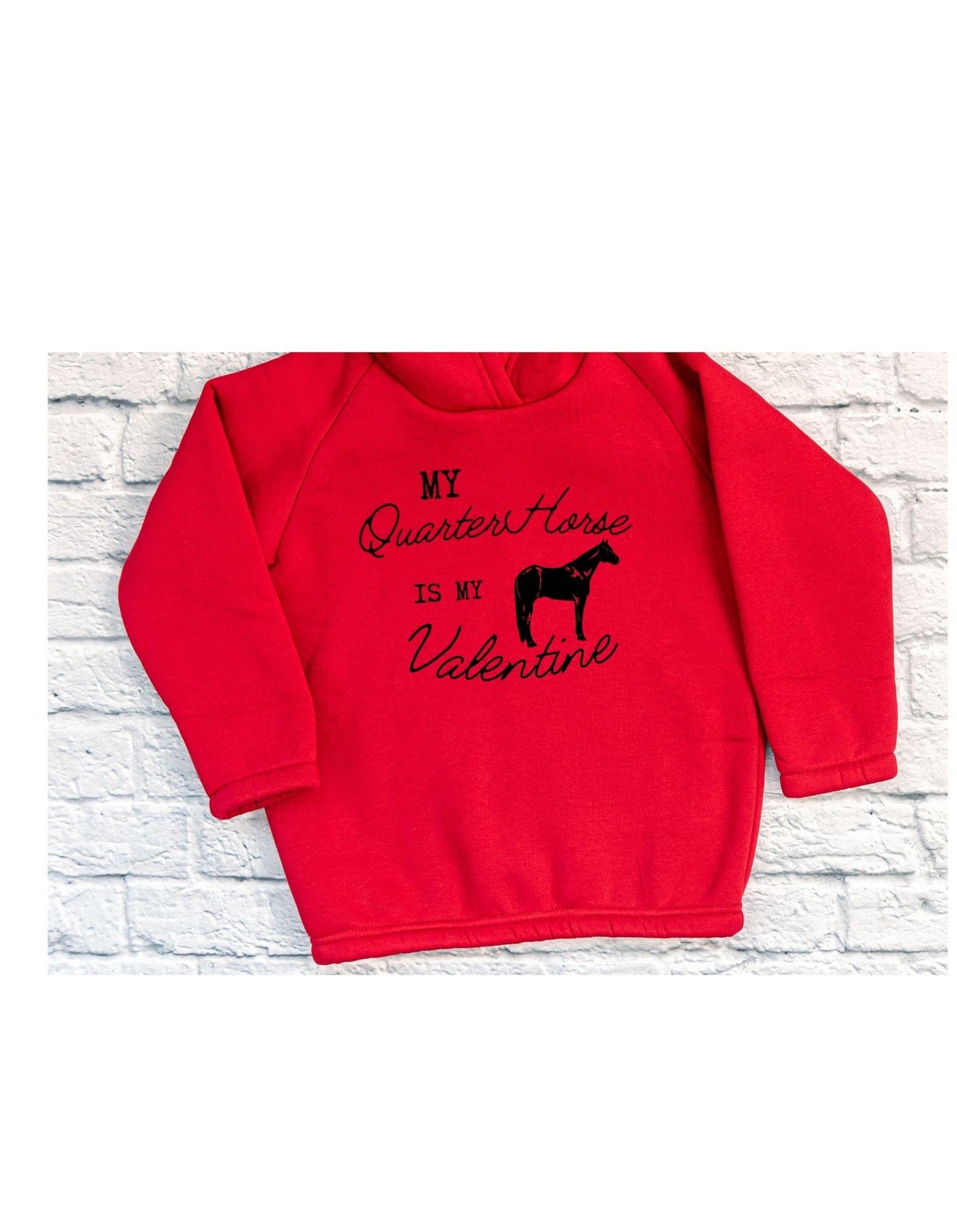 Red sweatshirt with black text and horse graphic on a white brick background