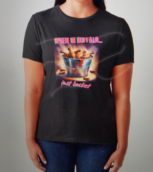 A black t-shirt with a graphic print of buffalo wings and the text 'When in Buffalo... just bucket it!'